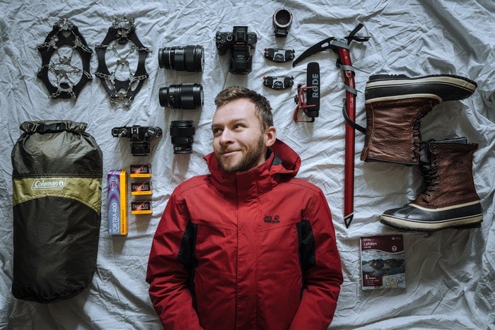 Man laying next to camera equipment laid out on a bed