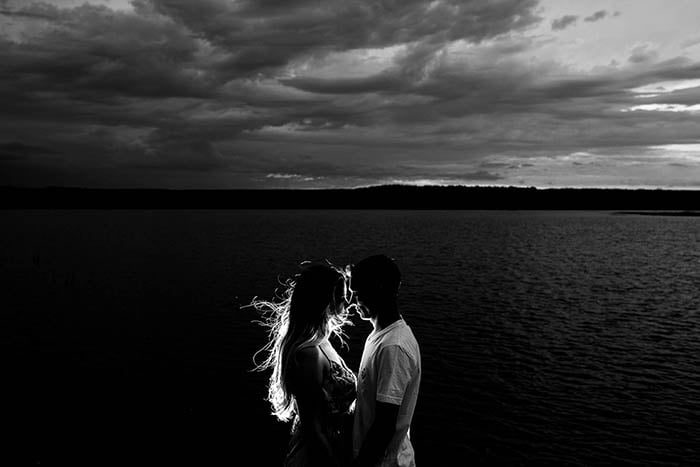 Black and white portrait of a couple with a view over the ocean in the background.