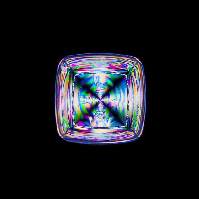 A small food container displaying rainbow effect patterns from photoelasticity