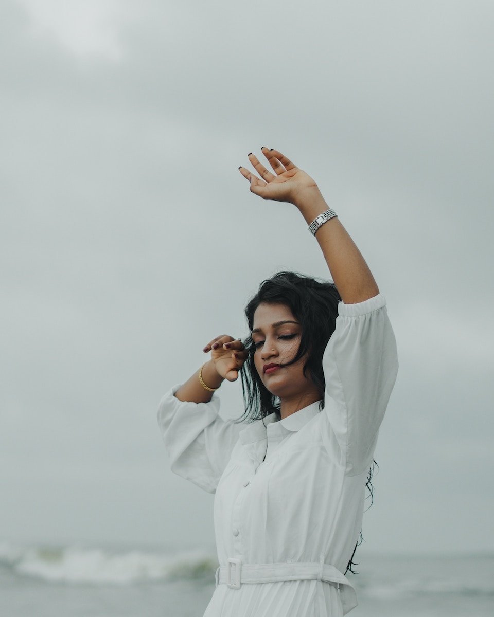 A woman in a white dress posing with her arm up