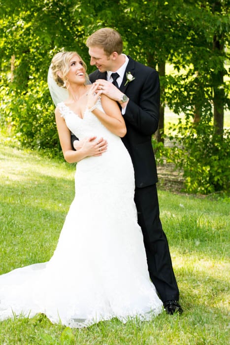 A wedding portrait of bride and groom posing together and laughing, leaning to the right