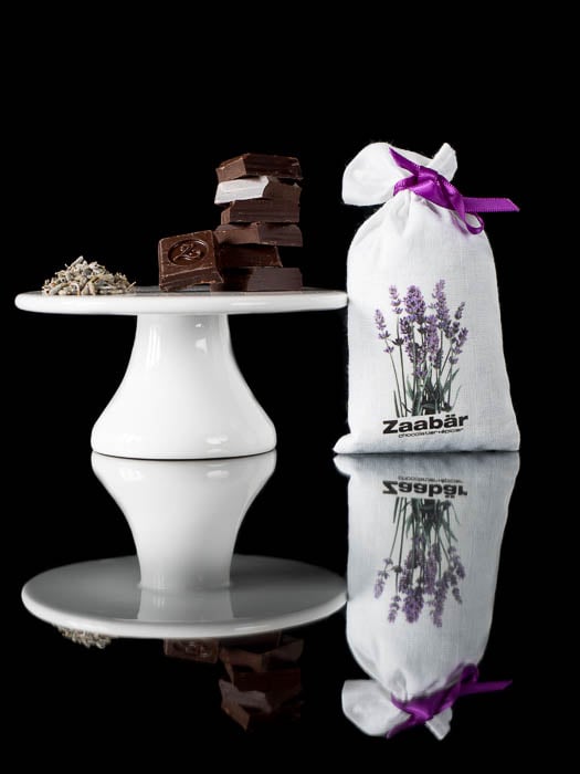 Squares of chocolate on a cake stand with a lavender bag next to it