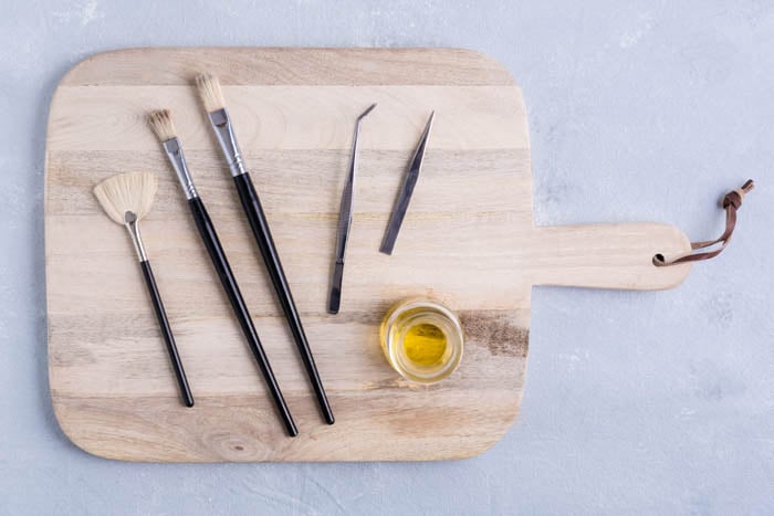 brushes and tweezers for food photography arranged on a wooden board