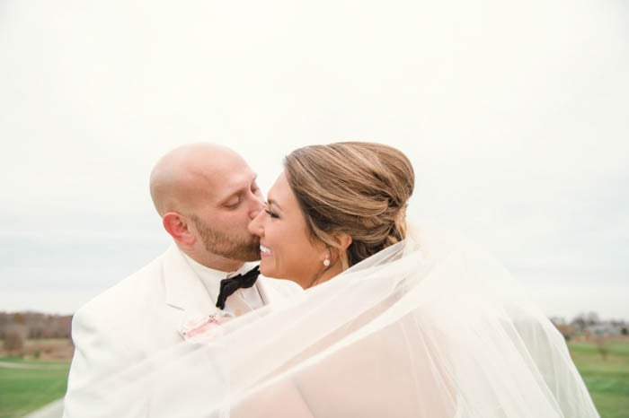 Wedding portrait of the couple posing outdoors with the veil