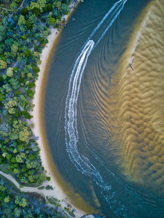 drone photography capturing the contrasting textures of a forest, coast, water and sand