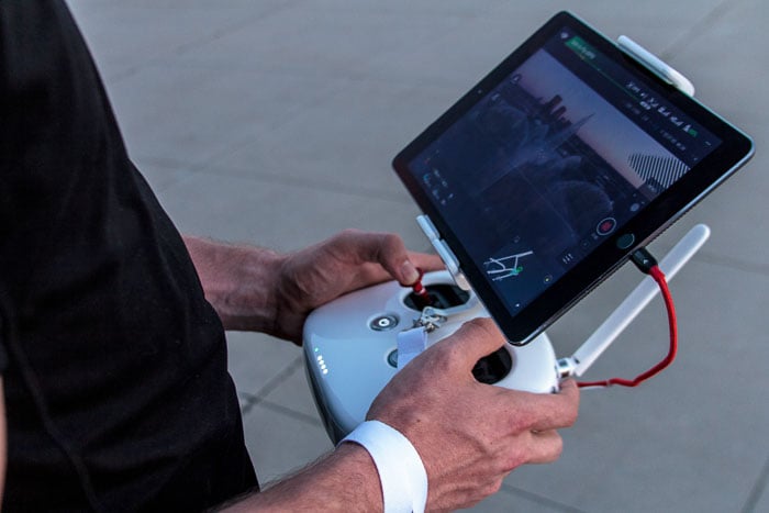 image of a man using a tablet for controlling drone landscape photography