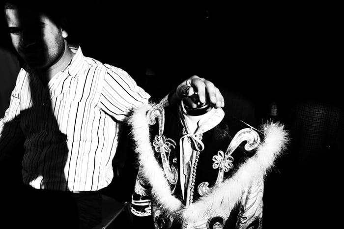 black and white street portrait from Istanbul, a man rests his hand on a shop mannequin traditional costume. 