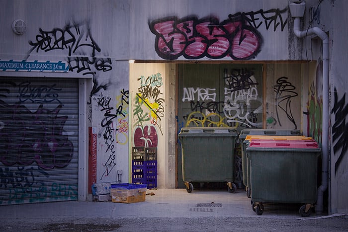 Creative street photography of buildings with graffiti and rubbish bins.