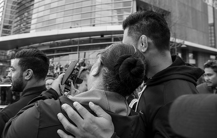 Black and white photo of a couple taking a selfie in a busy street scene. Creative street photography