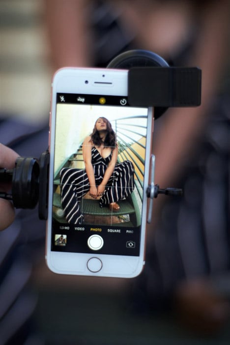 Smartphone with an image of a girl posing on the screen, held by a a smartphone tripod holder - ergonomic phone set-up for smartphone fashion photograph