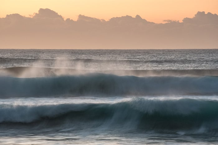 Blurred waves seascape with orange and yellow sky.
