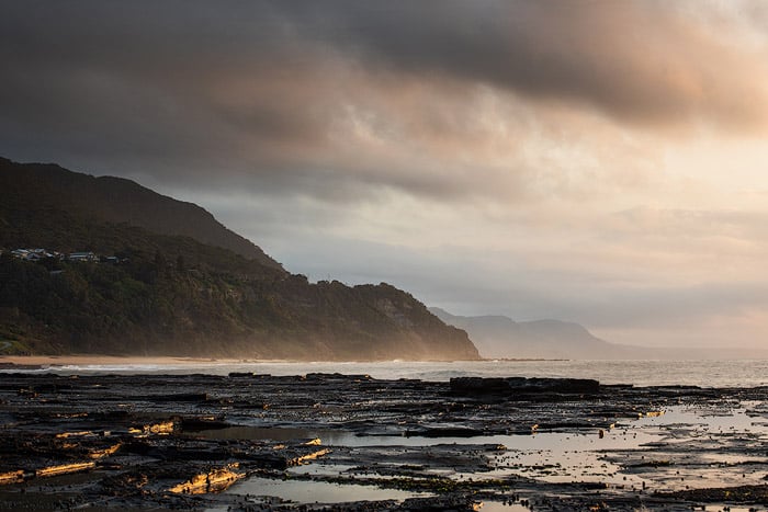 Calm evening seascape with overcast sky and mountains.