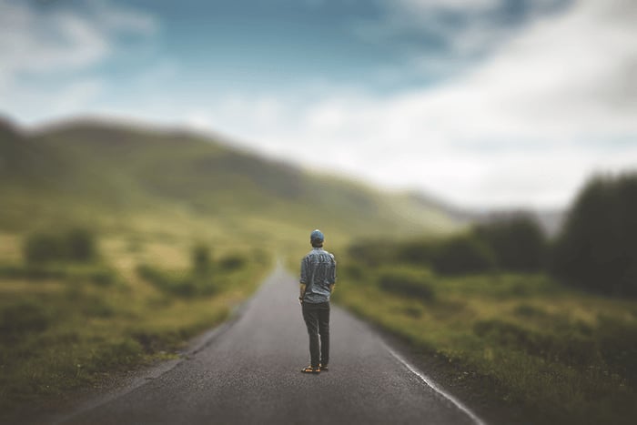 a man standing in the middle of the road, blurred landscape background