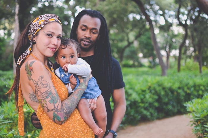 Family portrait photo of a couple posing with their baby outdoors