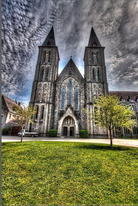 An over processed HDR photograph of Maredsous Abbey with black clouds, halos, and overcooked looks.