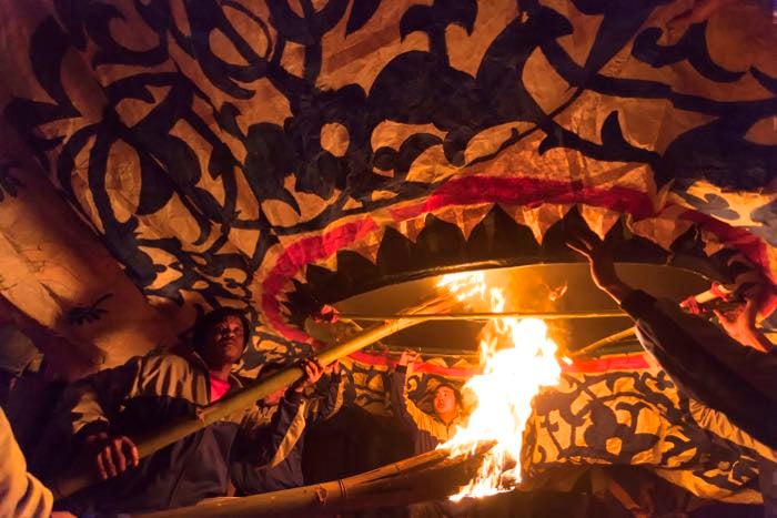 Night photography of men lighting a big lantern- travel photography checklist.