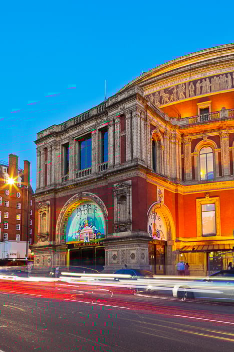 A night photograph of a building with long exposure light trails of traffic. Travel photography shot list.