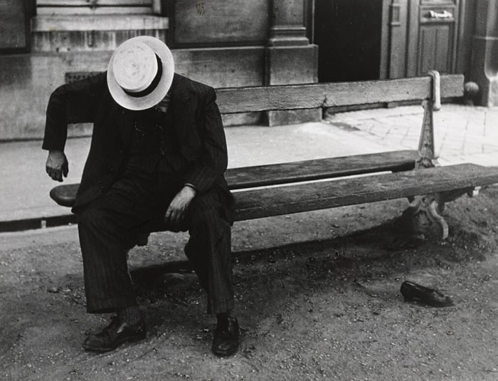 Man in hat sleeping while sitting on a bench