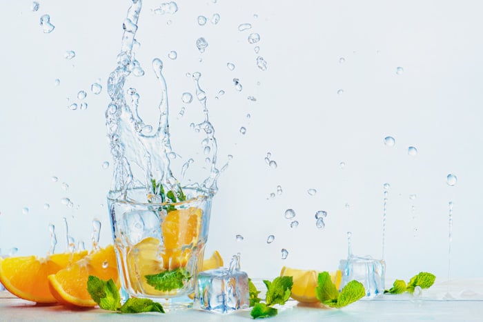 a creative food photography set up with oranges and water splashes on white background