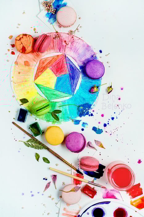 Flat lay idea: A birds eye view still life with colored macaroons, paintbrushes and leaves on painted surface