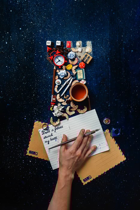 Creative still life flat lay with the silhouette of a fortress comprised of many small objects on a dark surface