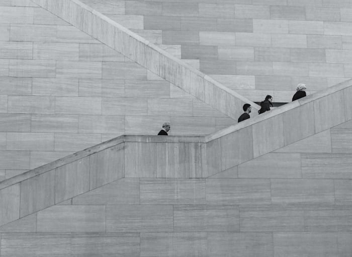 Black and white photo of four people climbing stone stairs