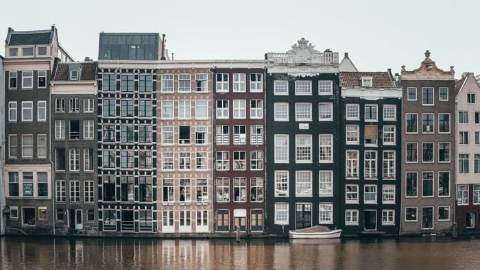 A row of buildings by a canal on an overcast day