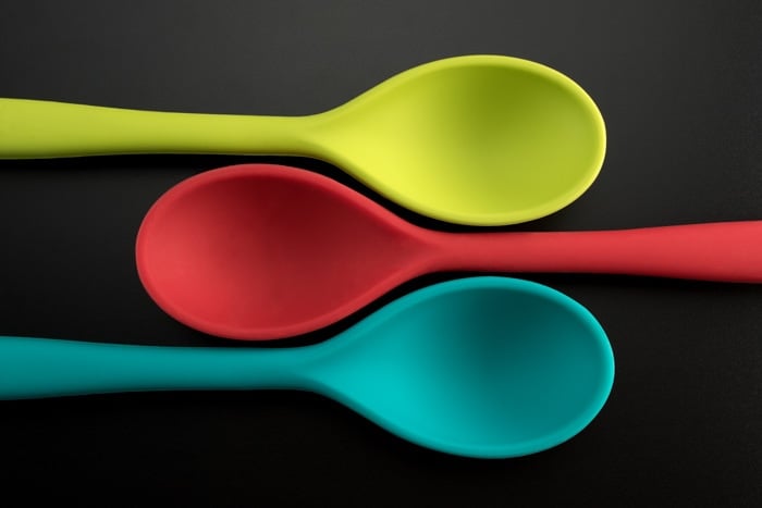flat lay product photography shot of three colored spoons against a grey background