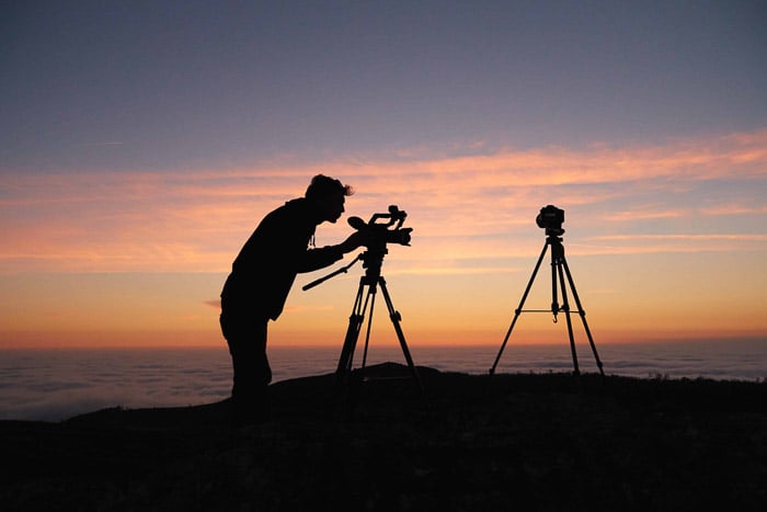 Silhouette of a photographer setting up a camera on a tripod at sunset – Smugmug review 