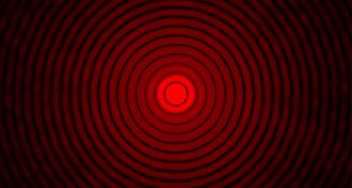 A black background with concentric, red circles and a red dot in the center.