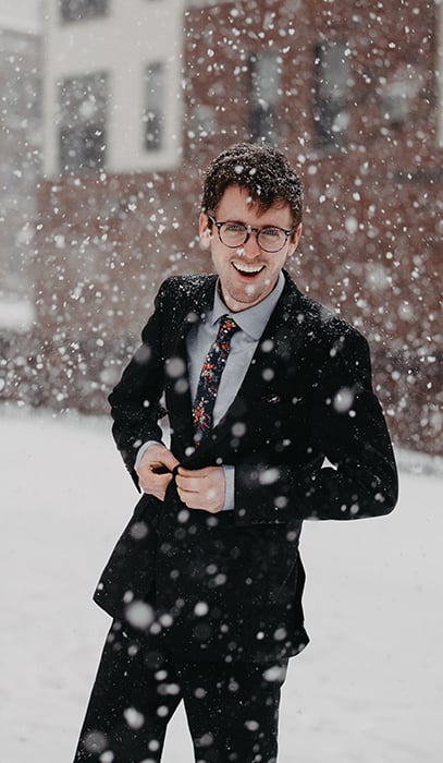Fun winter portrait of a male model posing casually under falling snow