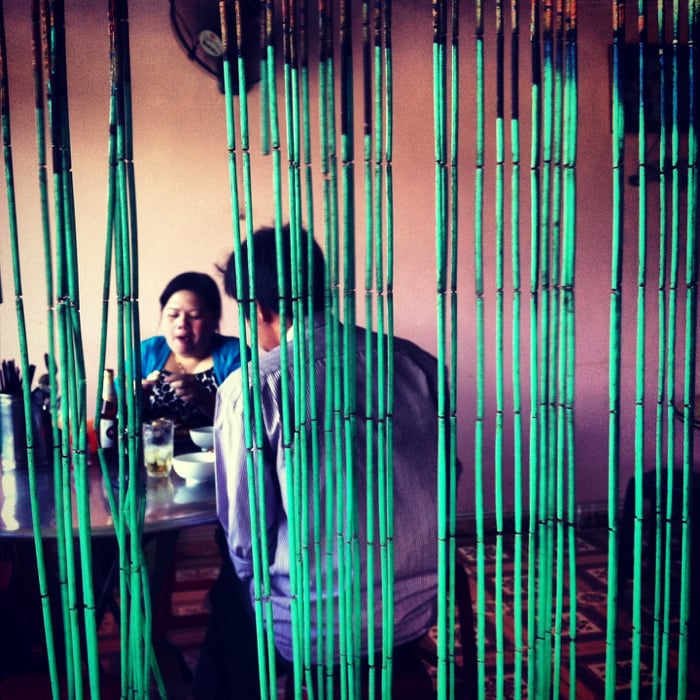 Candid shot of a couple eating dinner framed by the doorway blind.