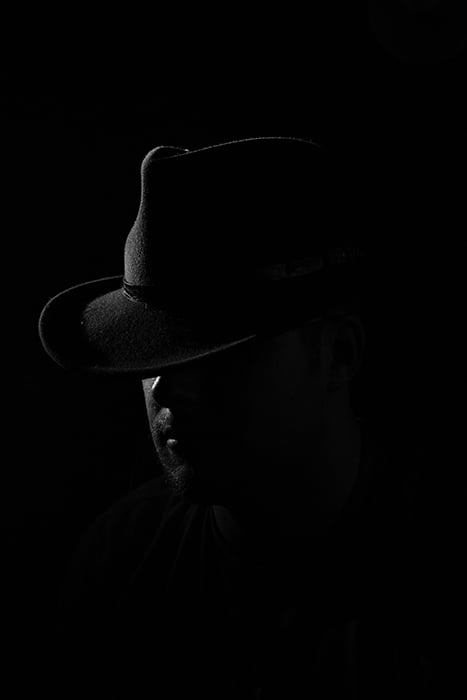 Film noir photography portrait of a male model wearing a cowboy hat