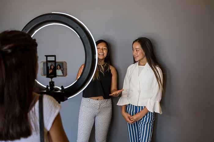 Two female models being photographed in a freelance photographer home studio space