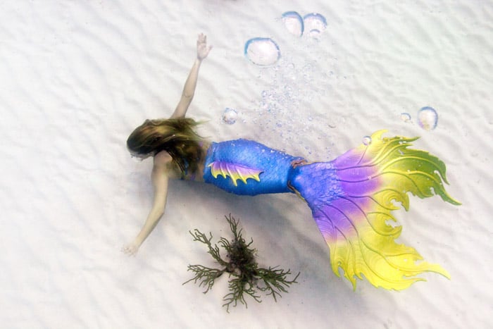 Dreamy underwater portrait of a female model with brightly colored mermaid tail