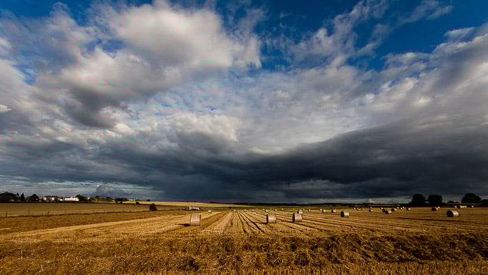 A typical wide angle landscape shot of a field under a cloudy sky