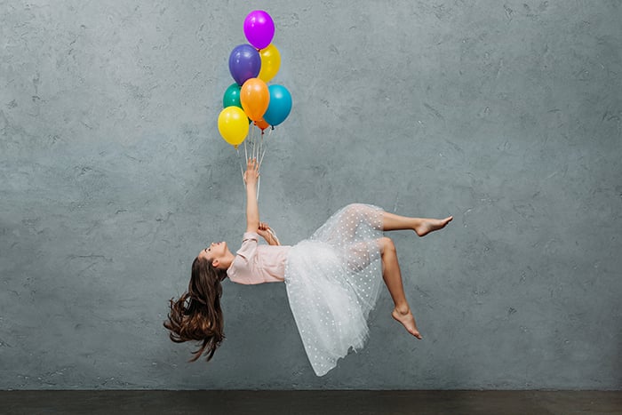 Young woman levitating with ballons.