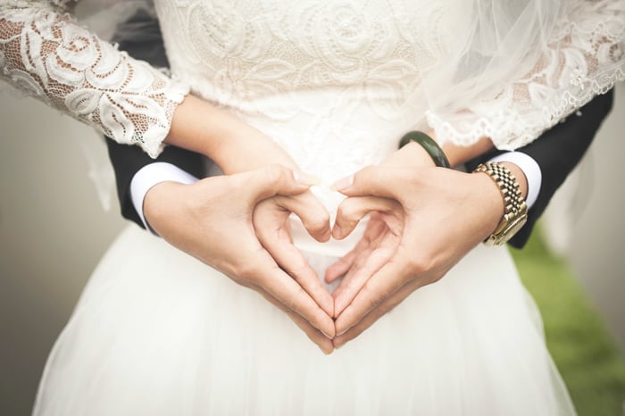 Artistic close up portrait of a newlywed couple holding each others hands in a heart shape - fine art wedding photography