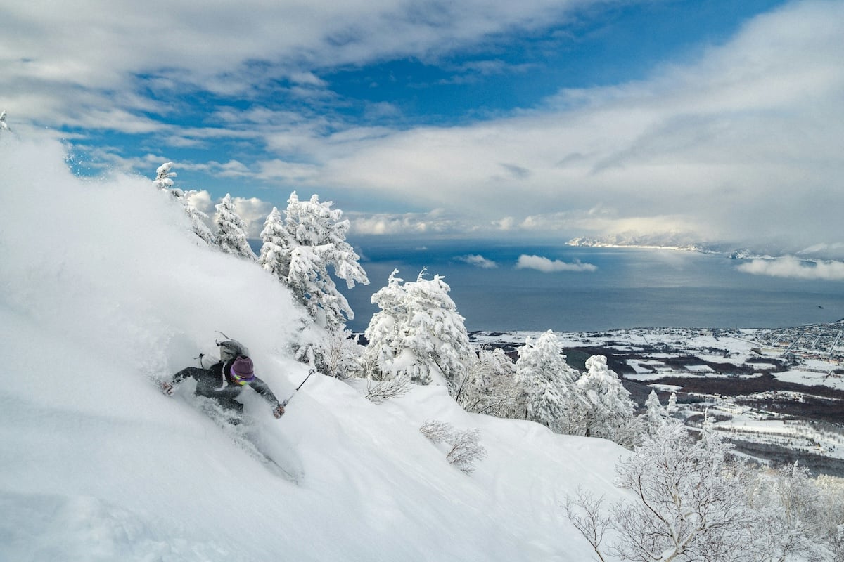An extreme downhill skier going down a snowy mountain with trees to show burst mode