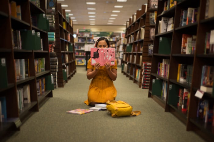 Conceptual portrait of a girl reading on a library floor shot using freelensing photography