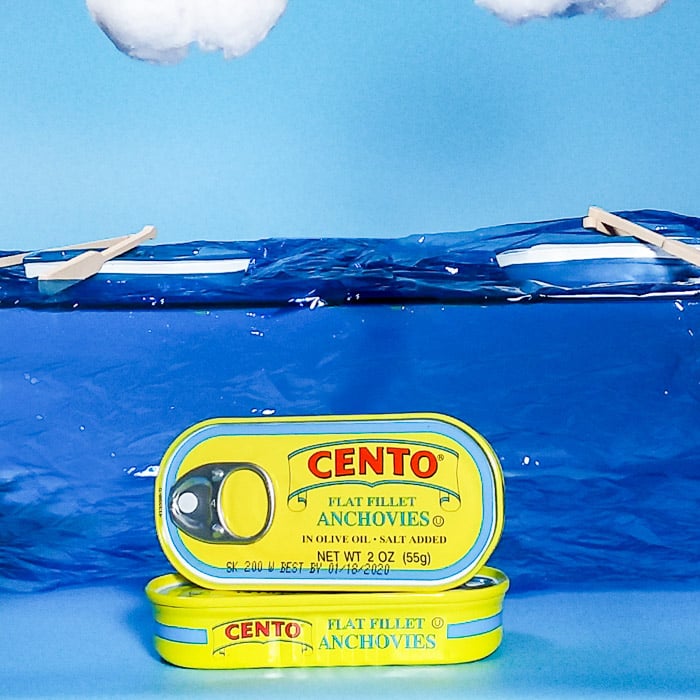smartphone product photography shot of cans of anchovies on painted background