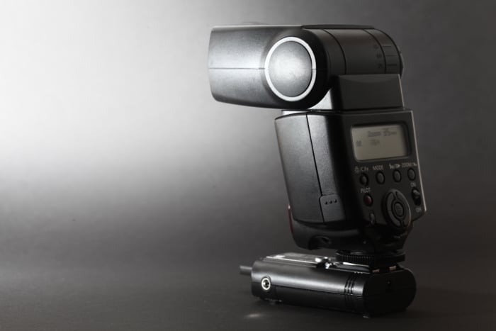 an old Canon 430EX II fires a flash at a black background - best camera flash