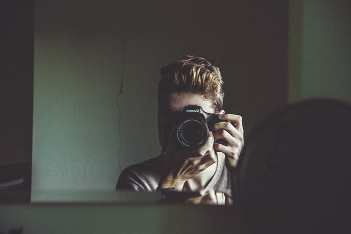 Young man taking picture of himself in mirror
