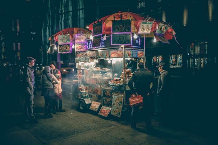 Street portrait of people at an outdoor foodstall at night - photography themes