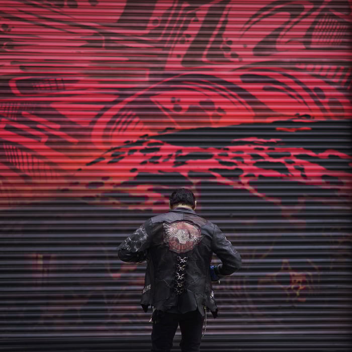 Atmospheric portrait of a male model posing moodily by a graffiti painted wall