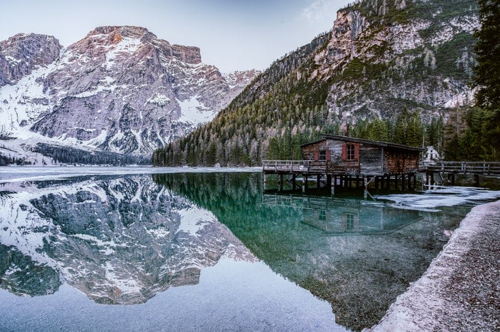 a long cabin over a lake surrounded by mountains, utilizing dynamic range in photography
