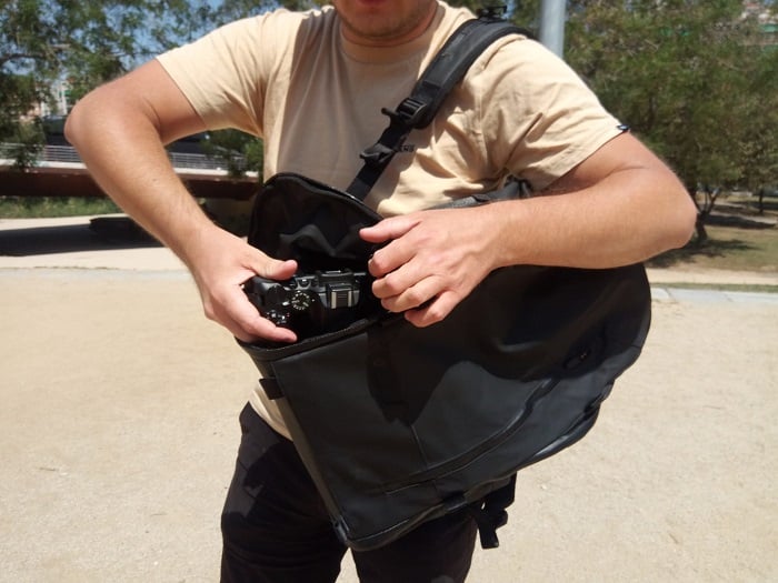 Young man using side access of Wandrd Duo Daypack to retrieve camera