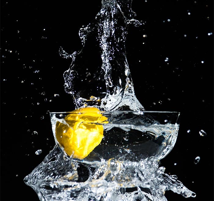 A photo of a lemon dropped into a bowl of water, causing a splash