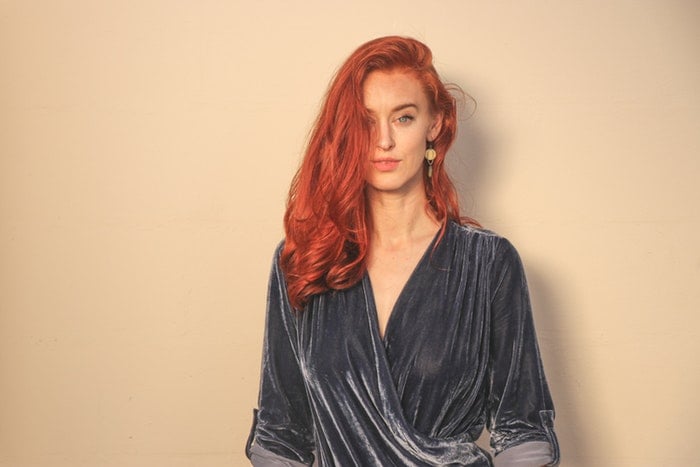 A girl standing in front of a peach colored backdrop