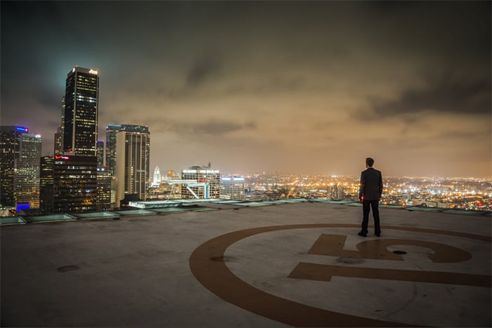 A man standing on the roof of a building with a city skyline in the background